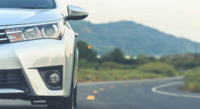 Front view of a silver sedan vehicle parked on a paved roadway in the mountains.